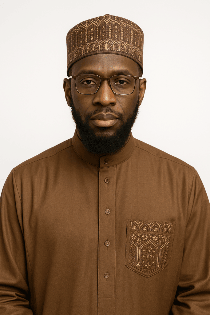Sheikh Muhammad Musa, Islamic advisor, with a beard and glasses, wearing a brown thobe and kufi. He is a spiritual mentor for the Muslim community and advocates for 100% transparency in donation management, supported by SOL.